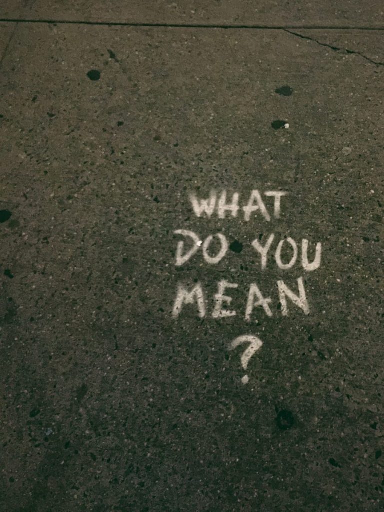 "What do you mean?" painted on concrete sidewalk
