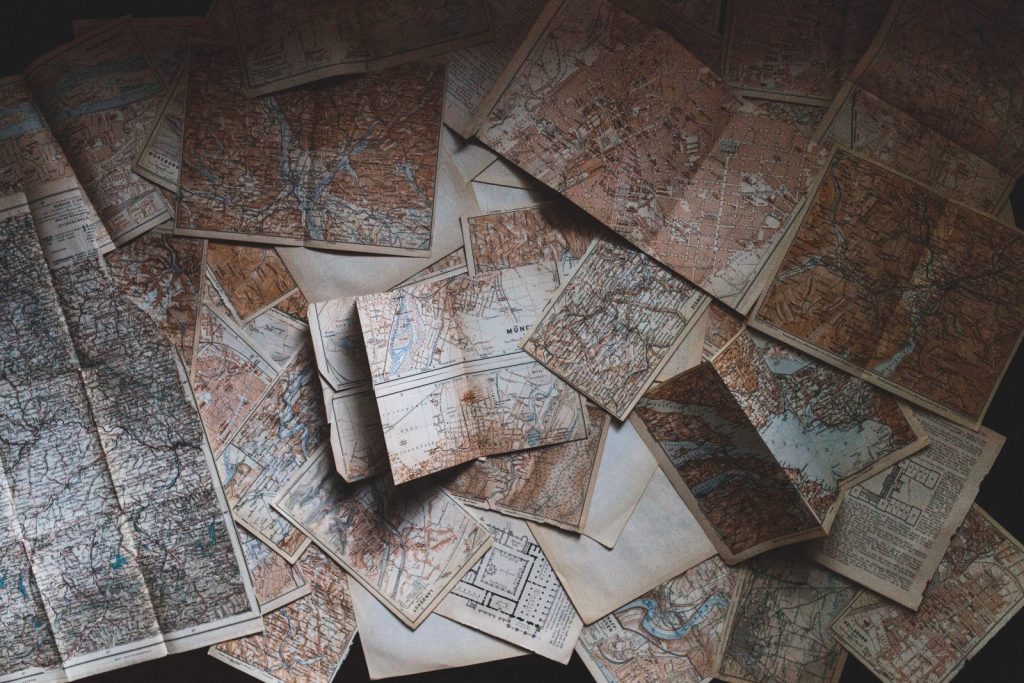 Faded maps overlapping and strewn across a table.