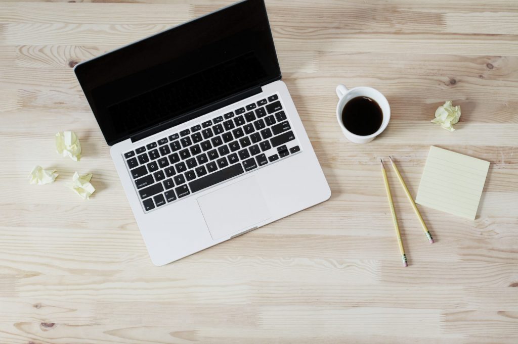 Laptop, coffee, pencils, crumpled paper