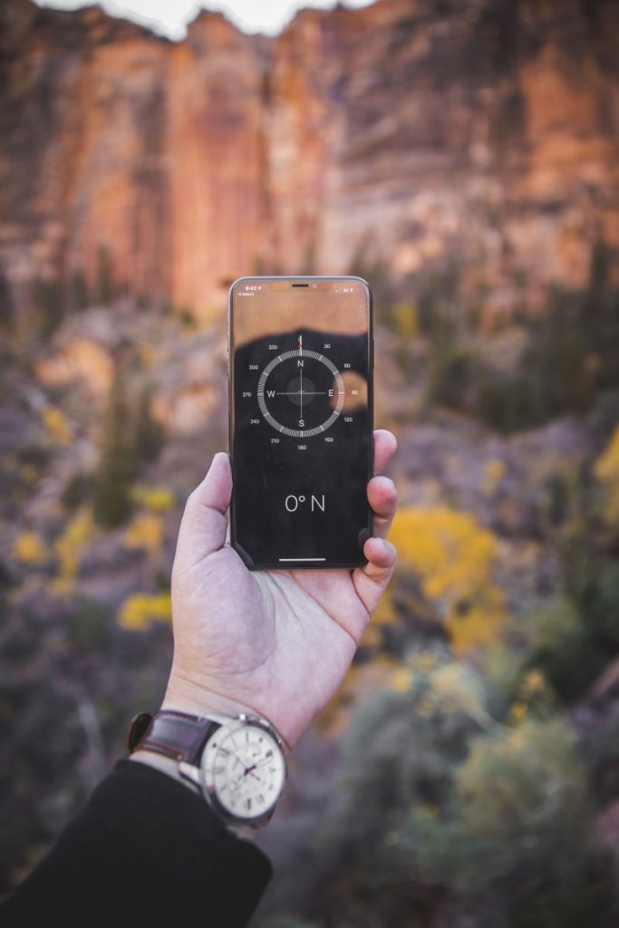 A hand holds up a compass on a phone.