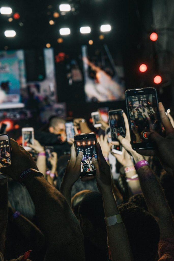 Lots of people hold smartphones up to take a photo